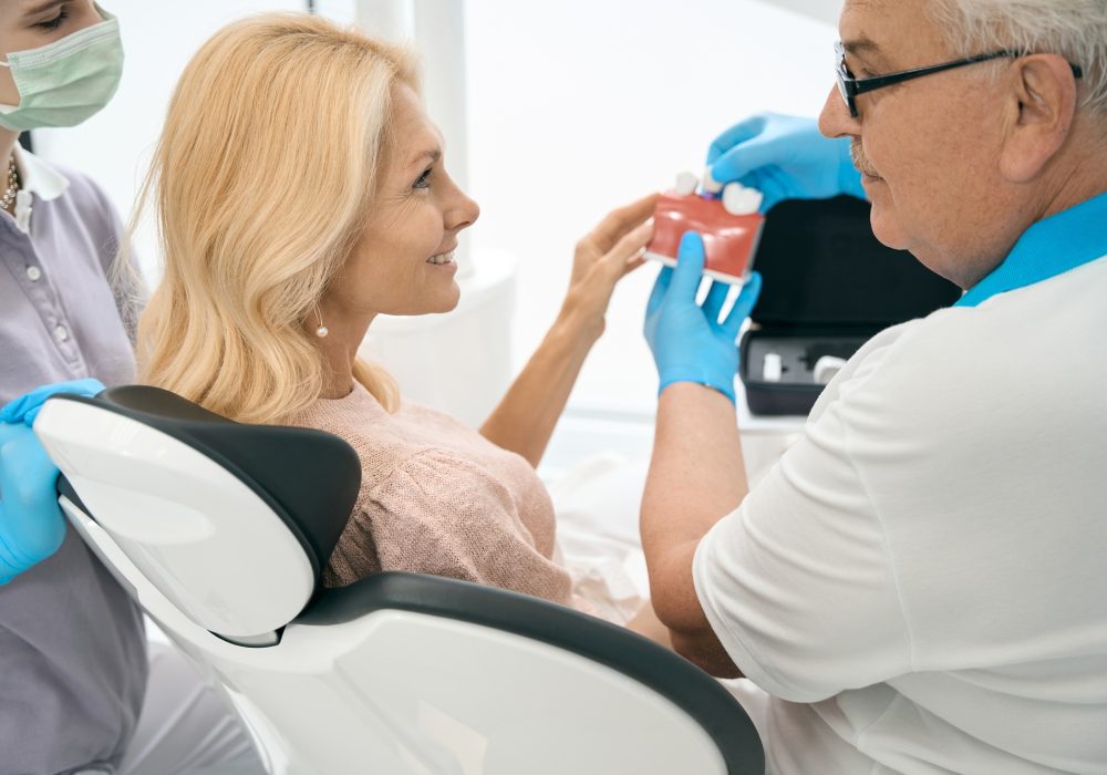 Dentist holding model of teeth with dental implant