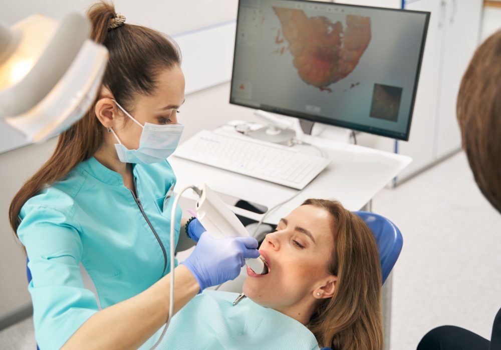 Dentist scanning woman teeth with dental intraoral 3D scanner